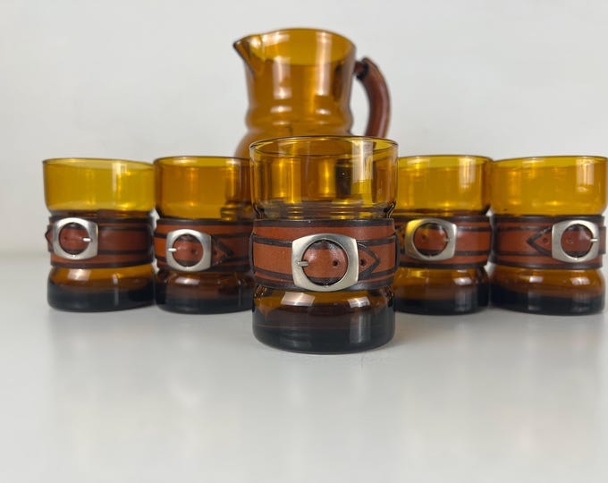 Great set of 5 amber colored drinking glasses with leather belts and metal buckles. 1960s retro mid century modern design