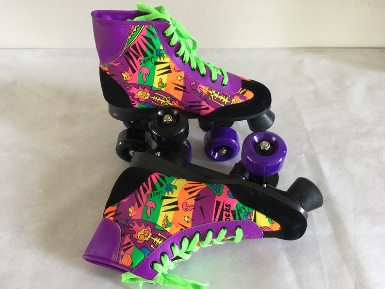 May include: A pair of purple and black roller skates with neon green laces and colorful graphic print. The print features flames, skulls, and the word "Socks".