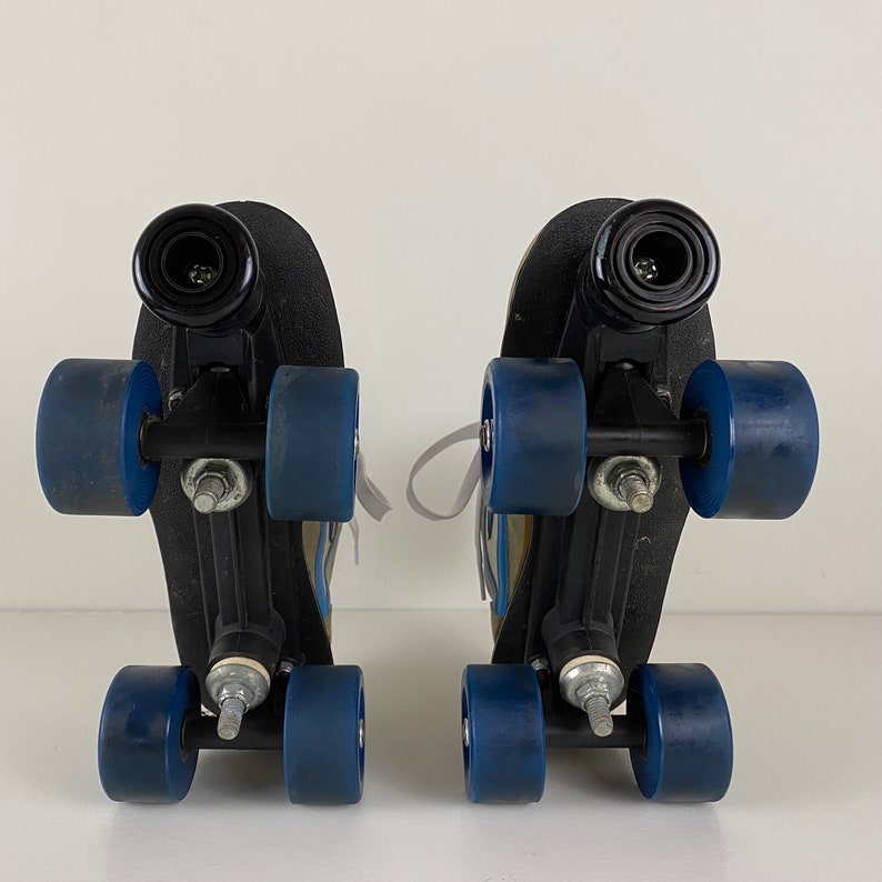 May include: A pair of black roller skates with blue wheels. The skates have a white strap and a black buckle.