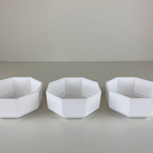 Peut inclure: Trois bols en céramique octogonaux blancs. Les bols sont tous de la même taille et de la même forme, et ils sont disposés en rangée sur une surface blanche.