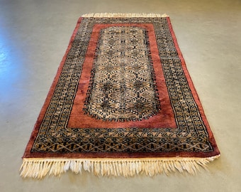 Small colorful oriental rug in red, brown, black, green and off white accents, hand made vintage from the 1970's