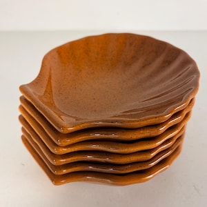 Op de afbeelding: Een set van drie keramische mokken met een gespikkelde, matte afwerking. De mokken zijn in de tinten crème, lichtgrijs en donkergrijs. Elke mok heeft een eenvoudig, minimalistisch ontwerp, perfect voor koffie of thee.