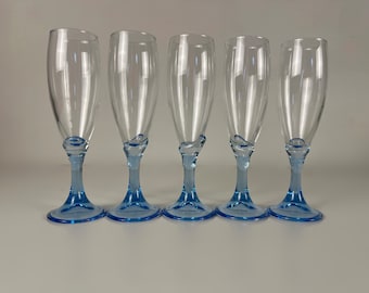 Puede incluir: Cinco copas de champán de vidrio transparente con bases azules. Las copas tienen un giro único en el tallo.