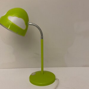 May include: A green desk lamp with a white cloud design on the shade. The lamp has a flexible arm and a round base.