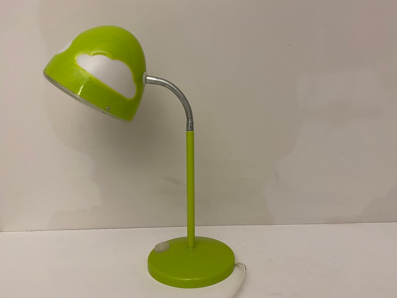 May include: A green desk lamp with a white cloud design on the shade. The lamp has a flexible arm and a round base.