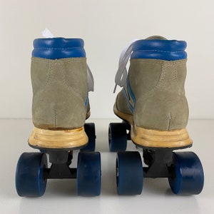 May include: A pair of vintage roller skates with gray suede boots, blue and white striped accents, and blue wheels.