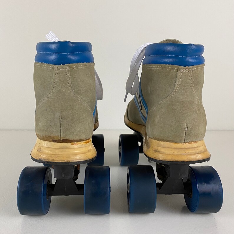 May include: A pair of vintage roller skates with gray suede boots, blue and white striped accents, and blue wheels.