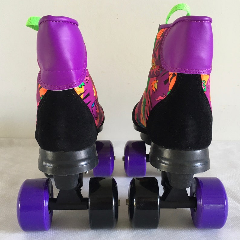 May include: A pair of black and purple roller skates with colorful abstract patterns on the boots. The skates have purple wheels and black frames.