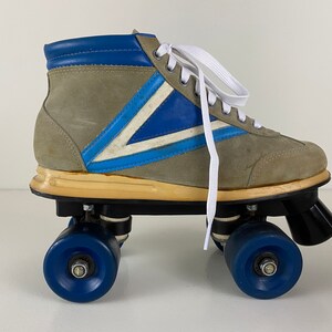 May include: A pair of vintage roller skates with a gray suede upper, blue and white accents, and white laces. The skates have black wheels with blue rims.