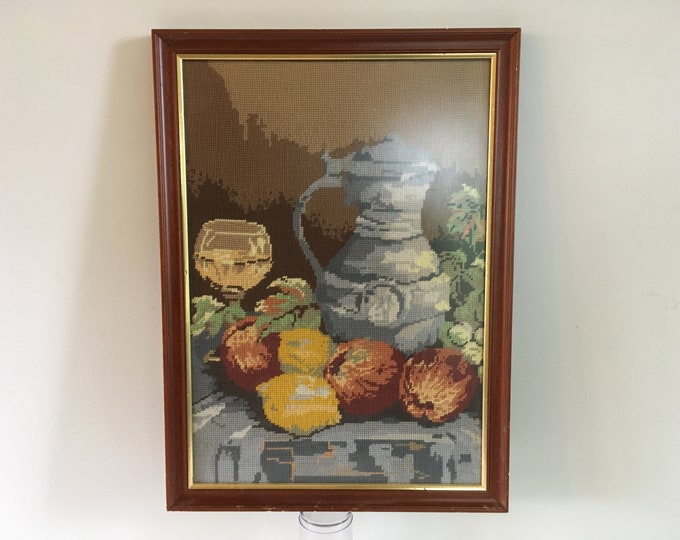 Cross stitched embroidery painting in wooden frame, still life with some fruit wine and wine jug mid century modern wall art from the 1970's