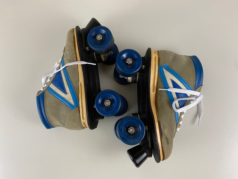 May include: A pair of vintage roller skates with gray suede boots, blue and white accents, and black wheels.