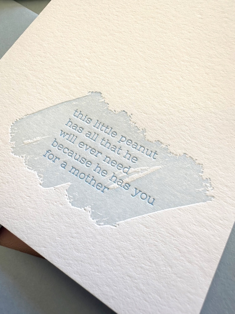 May include: A light blue card with a white background and a blue text overlay. The text reads: "this little peanut has all that he will ever need because he has you for a mother."