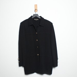 May include: A black blazer with a collared neckline and gold-colored buttons. The long-sleeved jacket is hanging on a black hanger against a white background. The blazer has a classic, tailored design.