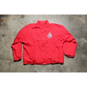 May include: A bright red windbreaker jacket with a full-length front zipper, long sleeves, and elastic cuffs. On the upper left chest, there is a triangular logo with the text Basketball Coaches Seattle 90 printed in blue and white.