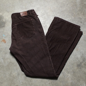 May include: A pair of brown corduroy pants. The pants have a classic five-pocket design with a brown leather patch on the back. The corduroy fabric has vertical ridges.
