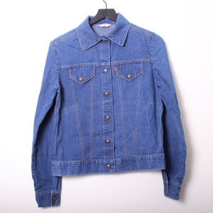 May include: A blue denim jacket with a button closure and two chest pockets.