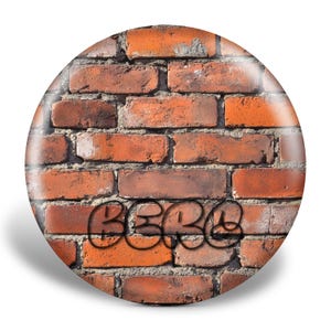 May include: A close-up of a brick wall with the word "BEBE" spray painted in black on the surface.