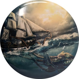 Op de afbeelding: Ronde decoratieve plaat met een dramatische nautische sc&egrave;ne. Een groot schip wordt aangevallen door een gigantische octopus in woelige wateren onder een stormachtige hemel. Het kunstwerk is gedetailleerd met tinten blauw, bruin en wit.