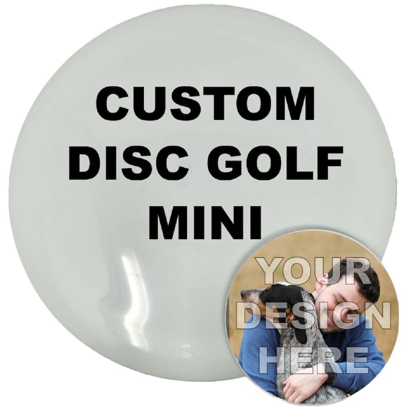 以下が含まれることがあります： 「CUSTOM DISC GOLF MINI」の黒い文字が入った白いディスクゴルフミニ。ディスク上の小さな円形の画像には、犬を抱きしめる人物と「YOUR DESIGN HERE」の文字が写っています。