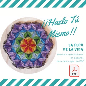 May include: A colorful string art design of the Flower of Life pattern, with a purple, blue, green, yellow, and red color scheme. The design is on a round wooden base. The text "Hazlo Tu Mismo!" is in the upper right corner of the image. The text "LA FLOR DE LA VIDA" is in the lower right corner of the image. The text "Patrón e instrucciones en Español para descargar en PDF" is below the text "LA FLOR DE LA VIDA". A PDF icon is in the lower right corner of the image.