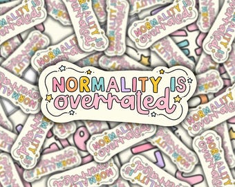 Op de afbeelding: Een sticker met de tekst "NORMALITY IS overrated" in kleurrijke bubbelletters. De sticker heeft een witte rand en is versierd met sterren. Andere stickers met hetzelfde ontwerp staan op de achtergrond.