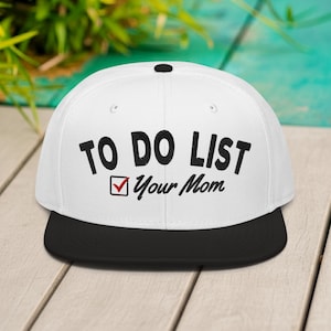 May include: A white baseball cap with a black peak. The cap displays the text "TO DO LIST" above "Your Mom" in black, with a red tick. The hat is a flat-brim style.