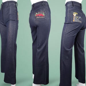 May include: Dark blue denim trousers with embroidered designs on the back pockets. The trousers have a high waist and a flared leg. The embroidery features a red car and a musical note design. A classic vintage style.