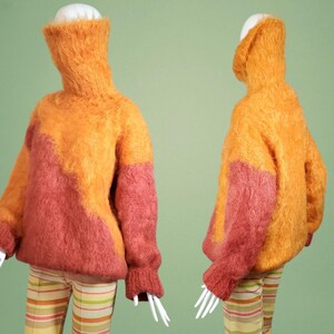 May include: A fuzzy, oversized sweater with a high neck. The sweater is a blend of orange and pink.