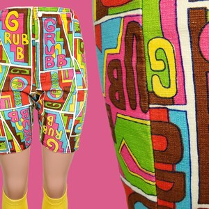 Peut inclure: Shorts vintage color&eacute;s avec un motif g&eacute;om&eacute;trique audacieux. Les shorts pr&eacute;sentent le mot "GRUBB" en grandes lettres, sur un fond de formes rouges, bleues, vertes et marron. Les shorts sont pr&eacute;sent&eacute;s sur un mannequin avec des chaussettes jaunes.
