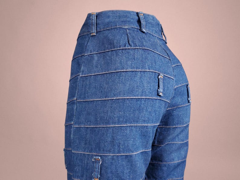 K&ouml;nnte beinhalten: Blaue Jeans mit horizontalen Nahtdetails. Die Jeans haben ein klassisches F&uuml;nf-Taschen-Design und einen Knopf- und Rei&szlig;verschluss. Die Jeans sind aus mittelblauem Denim.