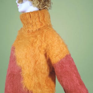May include: A fuzzy, two-toned turtleneck sweater with a bright orange front and a pink back.