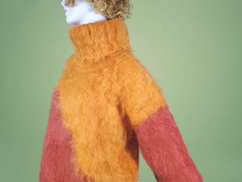 May include: A fuzzy, two-toned turtleneck sweater with a bright orange front and a pink back.