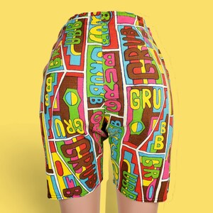 Peut inclure: Shorts color&eacute;s avec un motif g&eacute;om&eacute;trique marron, rouge, rose, jaune, vert et bleu. Les shorts pr&eacute;sentent le mot "GRUB" et d'autres textes dans le design. Les shorts sont pr&eacute;sent&eacute;s sur un fond jaune.