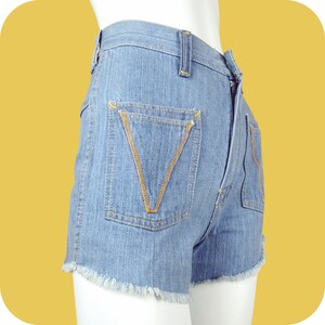 K&ouml;nnte beinhalten: Hellblaue Jeans-Shorts mit ausgefranstem Saum und kontrastierenden gelben N&auml;hten an den Taschen.