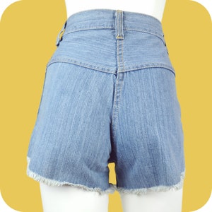 K&ouml;nnte beinhalten: Hellblaue Jeans-Shorts mit ausgefranstem Saum. Die Shorts haben eine hohe Taille und einen Knopfverschluss.