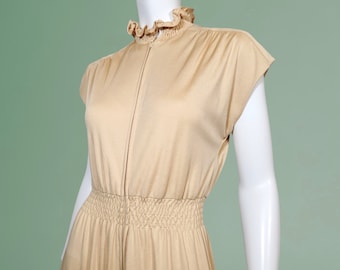 Peut inclure: Une robe beige sans manches avec un col à volants et une fermeture éclair sur le devant. La robe a un corsage ajusté et une jupe plissée.