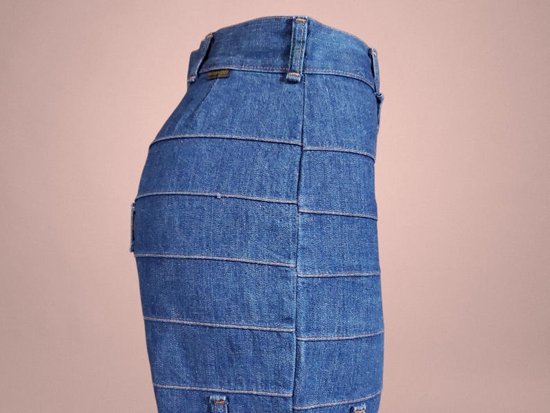 K&ouml;nnte beinhalten: Ein blauer Jeansrock mit horizontalen Bahnen. Der Rock hat ein klassisches F&uuml;nf-Taschen-Design und einen Bund mit G&uuml;rtelschlaufen. Der Denim hat eine mittlere Waschung und der Rock scheint eine Midi-L&auml;nge zu haben.
