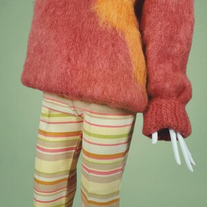 May include: A fuzzy pink and orange sweater with a striped pattern on the pants.