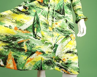 Peut inclure: Une robe verte, jaune et orange avec un imprimé de voiliers. La robe a une manche longue et une manchette à volants.