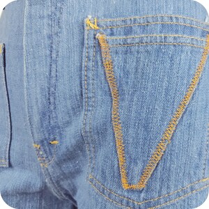 K&ouml;nnte beinhalten: Nahaufnahme einer blauen Jeans-Tasche mit gelber Steppnaht.