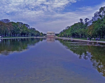 May include: A view of the Lincoln Memorial reflecting in a still pond with trees lining the sides of the pond.