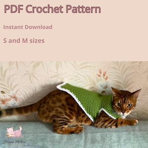 May include: A brown tabby cat wearing a green and white crochet garment. The image includes the text "PDF Crochet Pattern", "Instant Download", and "S and M sizes". The cat is lying on a blue surface.