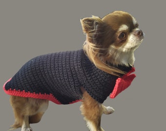 May include: A small brown and white chihuahua wearing a black crocheted sweater with a red crocheted bow tie.