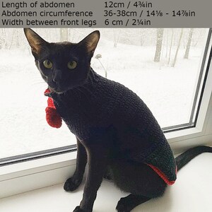 May include: A black cat wearing a red and black sweater sits on a windowsill. The cat's measurements are listed in inches and centimeters. Length from neck to tail: 30cm / 11 3/4in. Chest circumference: 37-39cm / 14 1/2 - 15 3/8in. Neck circumference: 27-29cm / 10 5/8 - 11 3/8in. Front leg circumference: 14-15cm / 5 1/2 - 5 7/8in. Length of abdomen: 12cm / 4 3/4in. Abdomen circumference: 36-38cm / 14 1/8 - 14 7/8in. Width between front legs: 6cm / 2 1/4in.
