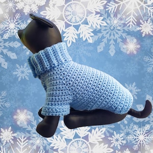 May include: A light blue crocheted dog sweater with a turtleneck. The sweater is on a mannequin dog against a blue background with white snowflakes.