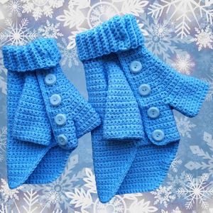 May include: Two blue crocheted dog sweaters with button closures. The sweaters are in a snowflake pattern background.