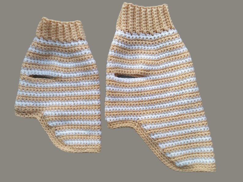 May include: Two crocheted striped leg warmers in beige and white. The leg warmers are made with a chunky yarn and have a simple design.