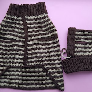 Może przedstawiać: Sweter dla psa z dzianiny szydełkowej w paski brązowe i beżowe z dopasowanym kapeluszem z dzianiny szydełkowej. Sweter ma długi tył i kr&oacute;tszy prz&oacute;d.