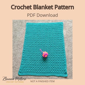 Może przedstawiać: Turkusowy koc szydełkowy z wzorem o fakturze, któremu towarzyszy kolorowa zabawka. Obraz zawiera tekst "Crochet Blanket Pattern PDF Download" i "Not a Finished Item". Koc jest prezentowany na neutralnej powierzchni.
