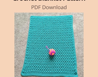 Może przedstawiać: Turkusowy koc szydełkowy z wzorem o fakturze, któremu towarzyszy kolorowa zabawka. Obraz zawiera tekst "Crochet Blanket Pattern PDF Download" i "Not a Finished Item". Koc jest prezentowany na neutralnej powierzchni.